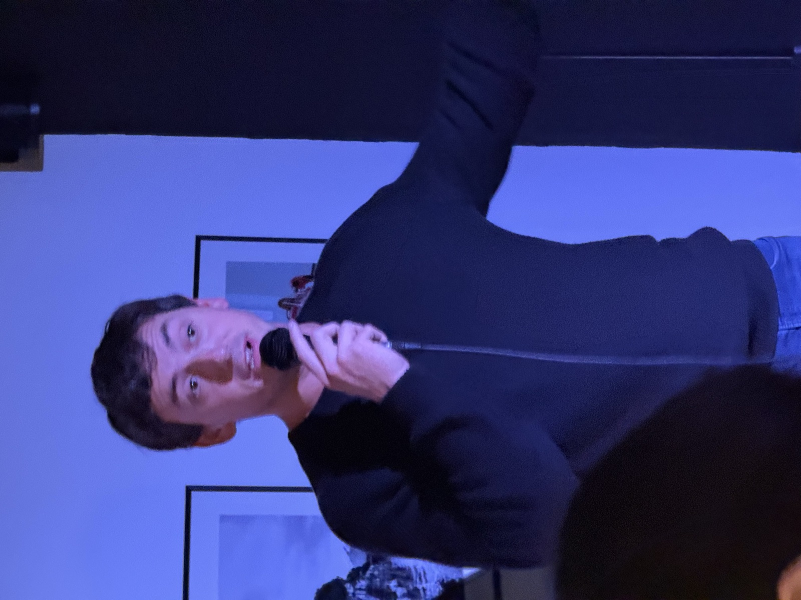 IN YOUR FACE Comedy, a comedian performing stand-up with a microphone on stage in Zürich (2025)