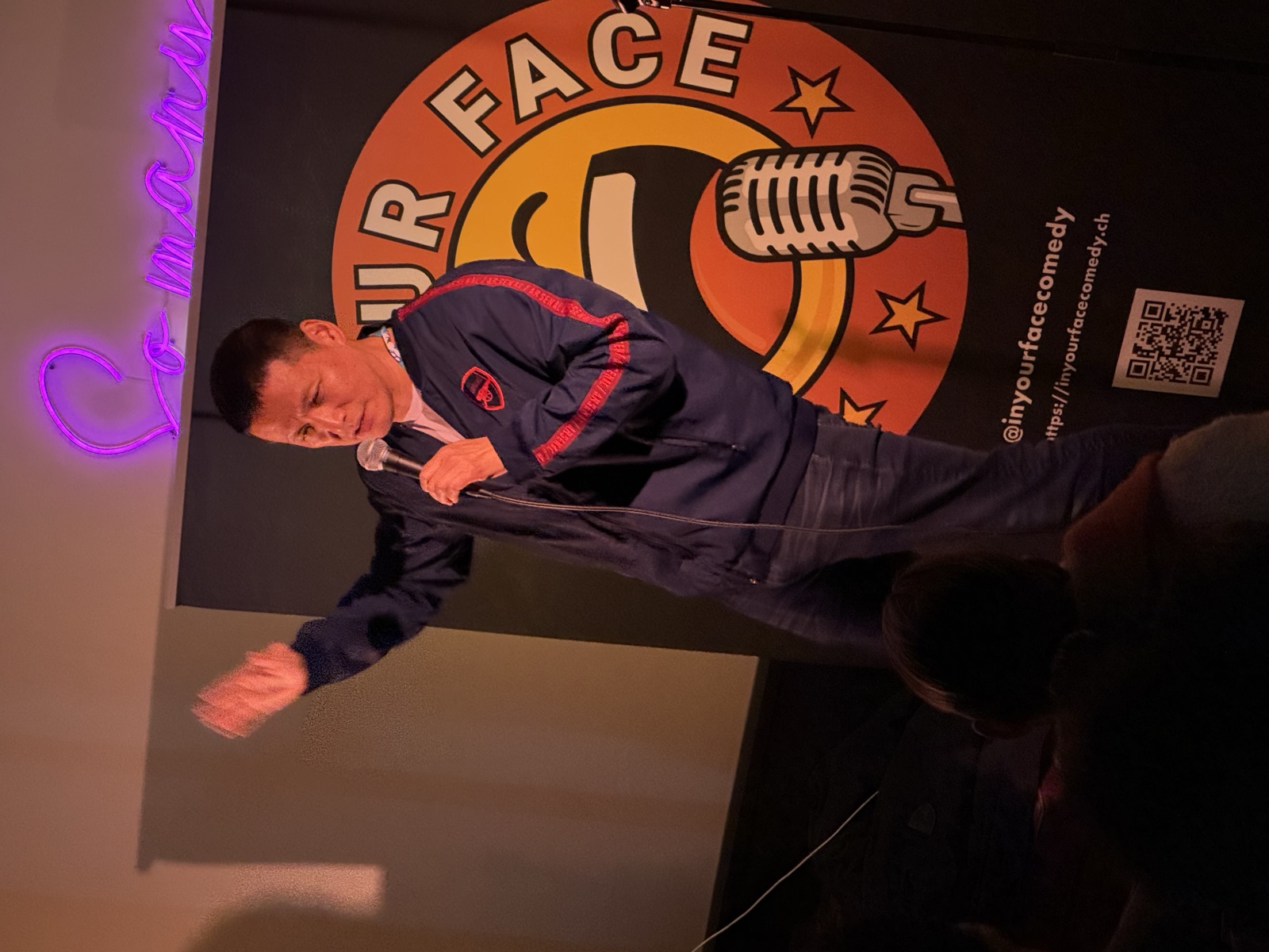 IN YOUR FACE Comedy, a comedian performing stand-up mid-bit on stage in Zürich (2024)